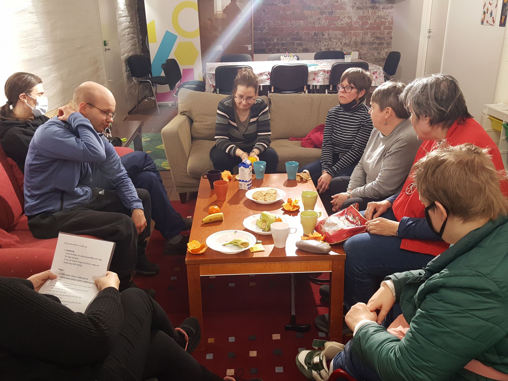 Bild från diskussionsträffen i Åbo, deltagarna sitter i soffor och på stolar och diskuterar".